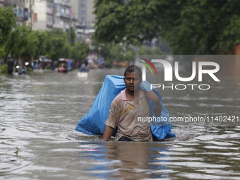 A man is going through a flooded street after heavy monsoon rainfall in Dhaka, Bangladesh, on July 12, 2024. (