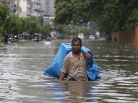 A man is going through a flooded street after heavy monsoon rainfall in Dhaka, Bangladesh, on July 12, 2024. (