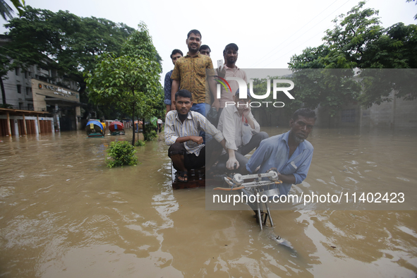 People are going through a flooded street after heavy monsoon rainfall in Dhaka, Bangladesh, on July 12, 2024. 