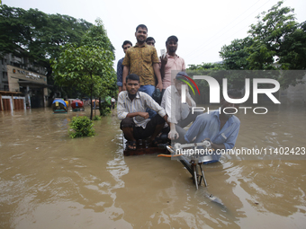 People are going through a flooded street after heavy monsoon rainfall in Dhaka, Bangladesh, on July 12, 2024. (