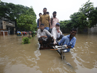 People are going through a flooded street after heavy monsoon rainfall in Dhaka, Bangladesh, on July 12, 2024. (