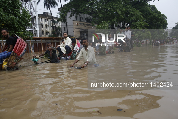 People are going through a flooded street after heavy monsoon rainfall in Dhaka, Bangladesh, on July 12, 2024. 