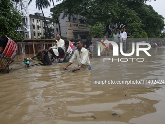 People are going through a flooded street after heavy monsoon rainfall in Dhaka, Bangladesh, on July 12, 2024. (