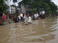 People are going through a flooded street after heavy monsoon rainfall in Dhaka, Bangladesh, on July 12, 2024. (