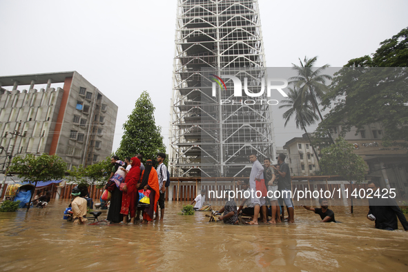 People are going through a flooded street after heavy monsoon rainfall in Dhaka, Bangladesh, on July 12, 2024. 