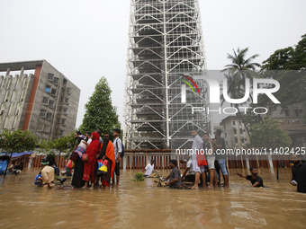 People are going through a flooded street after heavy monsoon rainfall in Dhaka, Bangladesh, on July 12, 2024. (