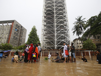 People are going through a flooded street after heavy monsoon rainfall in Dhaka, Bangladesh, on July 12, 2024. (