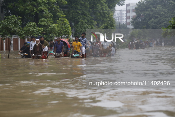 People are going through a flooded street after heavy monsoon rainfall in Dhaka, Bangladesh, on July 12, 2024. 