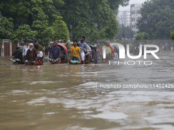 People are going through a flooded street after heavy monsoon rainfall in Dhaka, Bangladesh, on July 12, 2024. (