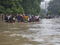 People are going through a flooded street after heavy monsoon rainfall in Dhaka, Bangladesh, on July 12, 2024. (