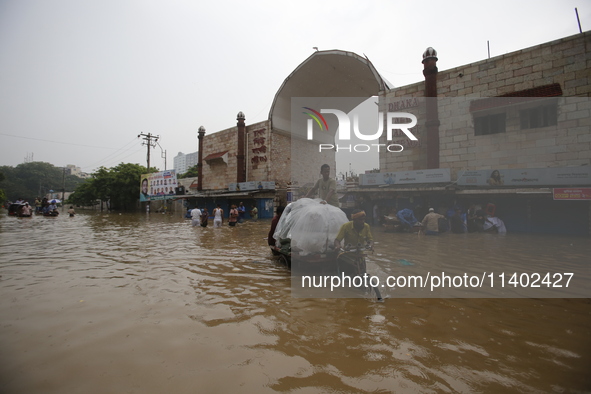 People are going through a flooded street after heavy monsoon rainfall in Dhaka, Bangladesh, on July 12, 2024. 