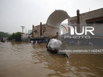 People are going through a flooded street after heavy monsoon rainfall in Dhaka, Bangladesh, on July 12, 2024. (