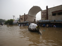 People are going through a flooded street after heavy monsoon rainfall in Dhaka, Bangladesh, on July 12, 2024. (