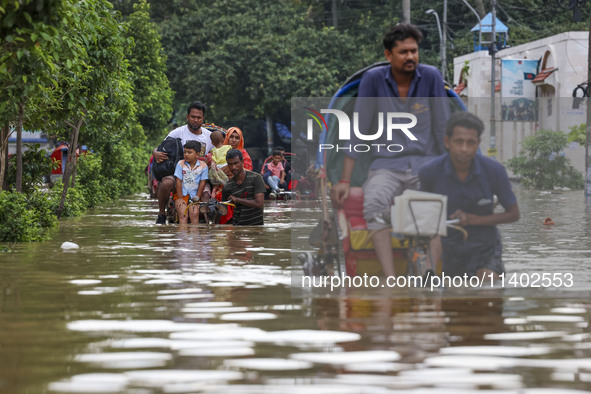 People are moving on rickshaws along a flooded street after a downpour in Dhaka, Bangladesh, on July 12, 2024. 