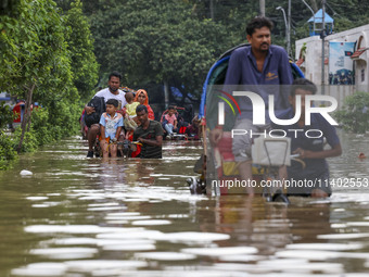 People are moving on rickshaws along a flooded street after a downpour in Dhaka, Bangladesh, on July 12, 2024. (