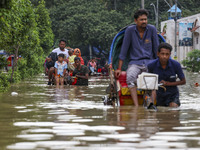 People are moving on rickshaws along a flooded street after a downpour in Dhaka, Bangladesh, on July 12, 2024. (