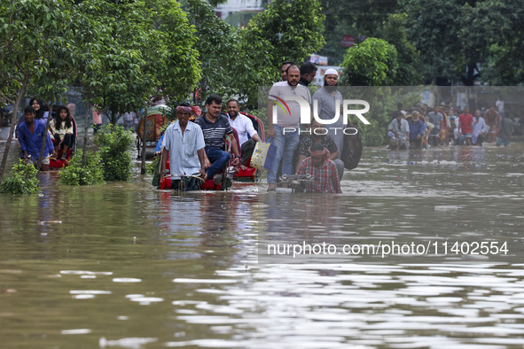 People are moving on rickshaws along a flooded street after a downpour in Dhaka, Bangladesh, on July 12, 2024. 