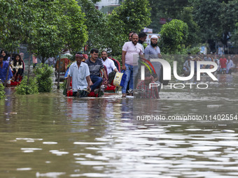 People are moving on rickshaws along a flooded street after a downpour in Dhaka, Bangladesh, on July 12, 2024. (