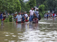 People are moving on rickshaws along a flooded street after a downpour in Dhaka, Bangladesh, on July 12, 2024. (