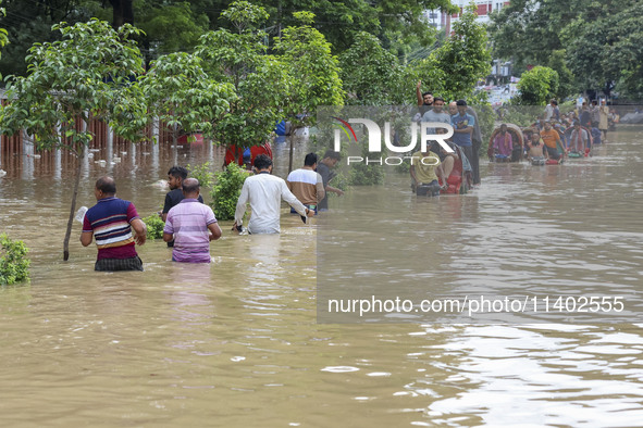 People are moving on rickshaws along a flooded street after a downpour in Dhaka, Bangladesh, on July 12, 2024. 