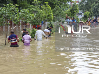 People are moving on rickshaws along a flooded street after a downpour in Dhaka, Bangladesh, on July 12, 2024. (