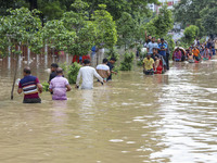 People are moving on rickshaws along a flooded street after a downpour in Dhaka, Bangladesh, on July 12, 2024. (