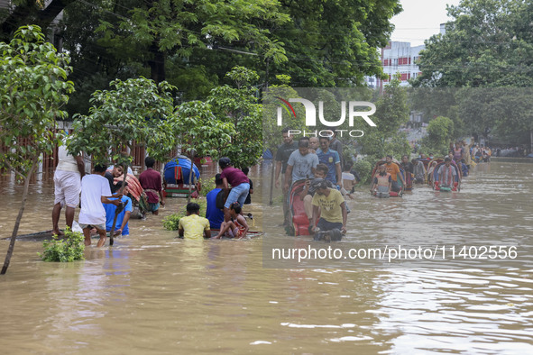 People are moving on rickshaws along a flooded street after a downpour in Dhaka, Bangladesh, on July 12, 2024. 