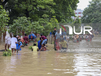 People are moving on rickshaws along a flooded street after a downpour in Dhaka, Bangladesh, on July 12, 2024. (