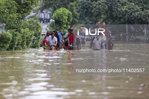 People are moving on rickshaws along a flooded street after a downpour in Dhaka, Bangladesh, on July 12, 2024. 