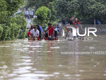 People are moving on rickshaws along a flooded street after a downpour in Dhaka, Bangladesh, on July 12, 2024. (