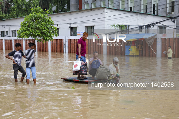 People are moving on rickshaws along a flooded street after a downpour in Dhaka, Bangladesh, on July 12, 2024. 