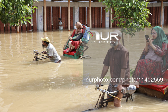 People are moving on rickshaws along a flooded street after a downpour in Dhaka, Bangladesh, on July 12, 2024. 