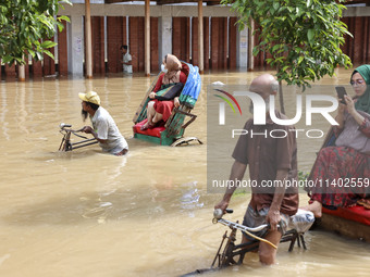 People are moving on rickshaws along a flooded street after a downpour in Dhaka, Bangladesh, on July 12, 2024. (