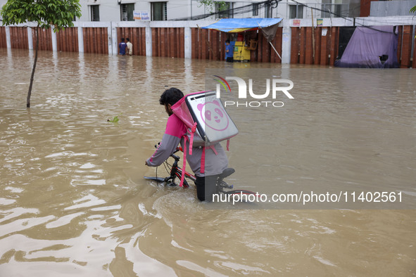 People are moving on rickshaws along a flooded street after a downpour in Dhaka, Bangladesh, on July 12, 2024. 