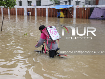 People are moving on rickshaws along a flooded street after a downpour in Dhaka, Bangladesh, on July 12, 2024. (