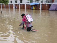 People are moving on rickshaws along a flooded street after a downpour in Dhaka, Bangladesh, on July 12, 2024. (