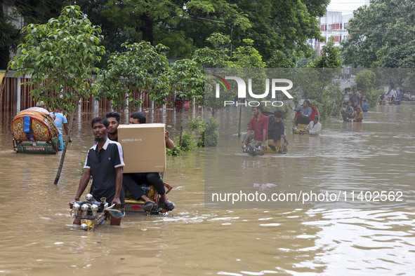 People are moving on rickshaws along a flooded street after a downpour in Dhaka, Bangladesh, on July 12, 2024. 