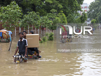 People are moving on rickshaws along a flooded street after a downpour in Dhaka, Bangladesh, on July 12, 2024. (