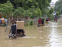 People are moving on rickshaws along a flooded street after a downpour in Dhaka, Bangladesh, on July 12, 2024. (