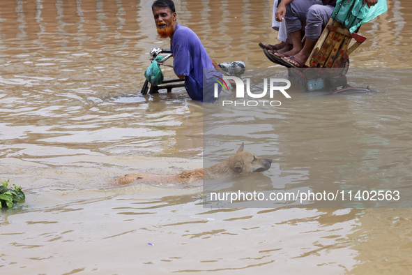 People are moving on rickshaws along a flooded street after a downpour in Dhaka, Bangladesh, on July 12, 2024. 