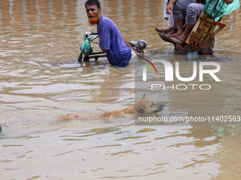 People are moving on rickshaws along a flooded street after a downpour in Dhaka, Bangladesh, on July 12, 2024. (