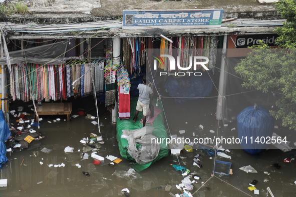 A street vendor is trying to keep his goods in a dry place after the market is waterlogged following a heavy downpour in Dhaka, Bangladesh,...