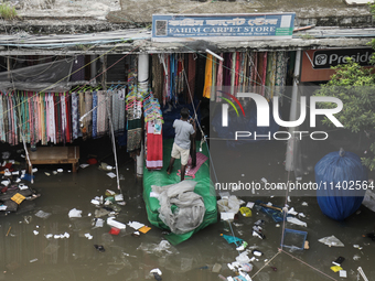 A street vendor is trying to keep his goods in a dry place after the market is waterlogged following a heavy downpour in Dhaka, Bangladesh,...