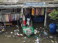 A street vendor is trying to keep his goods in a dry place after the market is waterlogged following a heavy downpour in Dhaka, Bangladesh,...