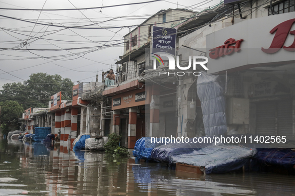 A street vendor is sitting on the rooftop of his store after the market is waterlogged after a heavy downpour in Dhaka, Bangladesh, on July...