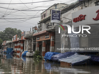 A street vendor is sitting on the rooftop of his store after the market is waterlogged after a heavy downpour in Dhaka, Bangladesh, on July...