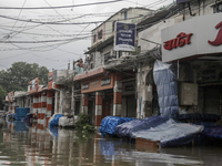 A street vendor is sitting on the rooftop of his store after the market is waterlogged after a heavy downpour in Dhaka, Bangladesh, on July...