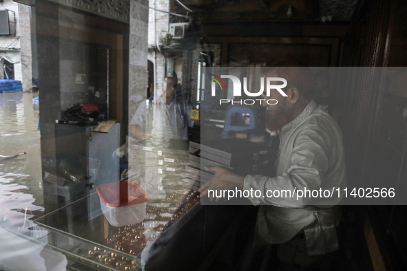 A jewelry shop owner is trying to keep his goods in a dry cabinet after the market is waterlogged following a heavy downpour in Dhaka, Bangl...