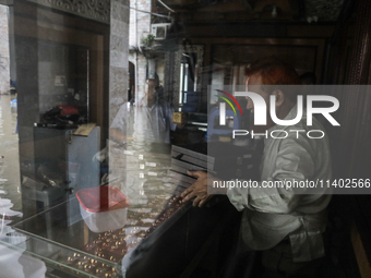 A jewelry shop owner is trying to keep his goods in a dry cabinet after the market is waterlogged following a heavy downpour in Dhaka, Bangl...