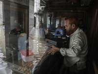 A jewelry shop owner is trying to keep his goods in a dry cabinet after the market is waterlogged following a heavy downpour in Dhaka, Bangl...